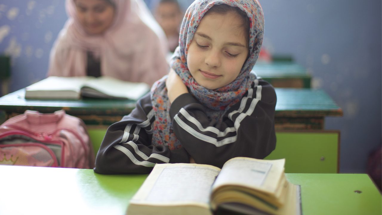 Enfant, jeune fille, qui lit le coran dans une salle de classe, en cours Enfant, jeune fille, qui lit le coran dans une salle de classe, en cours